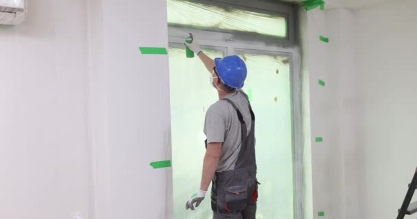 建筑工人用白色喷漆在聚氯乙烯窗户上涂刷一层 窗框的油漆和修理 — 图库视频影像