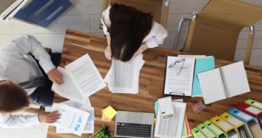 Ofis masasında çalışan iş adamları yeni pazarlama planlarını tartışıyor. Proje tablosu kullanılarak belge akış raporlarının istatistiklerini analiz et