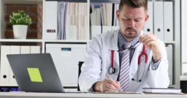 Genç doktor hasta tıbbi verilerini iş yerindeki karta yazar. Tıbbi kayıt tutma kavramı