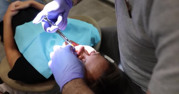 牙科医生在拔牙时注射止痛药 男医生在女性疼痛时注射止痛药 以清除临床慢动作中的病牙 — 图库视频影像