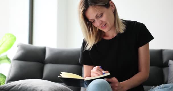 Zaměřená Žena Podnikatel Píše Týdenní Plány Papírovém Poznámkovém Bloku Pohovce — Stock video