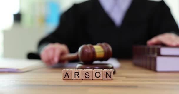 Arson是用拉丁文字母写在木制法庭桌旁的方块上的女法官在音块上敲木槌 财产恶意损坏慢动作 — 图库视频影像