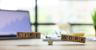 Tahta küplere yazılmış Hayat ve İş Sözcükleri hafif ofisteki iş yerindeki terazilerdeki dengeler üzerinde dengelenmiştir. Dengeli iş ve özel hayat konsepti ağır çekim