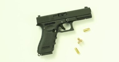 Beyaz masada boş tabanca ve stüdyoda mermiler. Atış poligonunda uzmanlar için silah araştırması. Tehlike ve risk kavramı