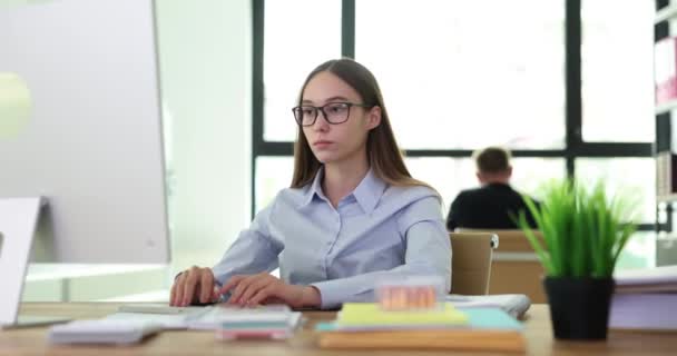 混乱し驚いた表情を持つオフィスの従業員は コンピュータのモニターを見ています 女性は衝撃的なニュースの遅い動きを読むメガネを取り除きます — ストック動画