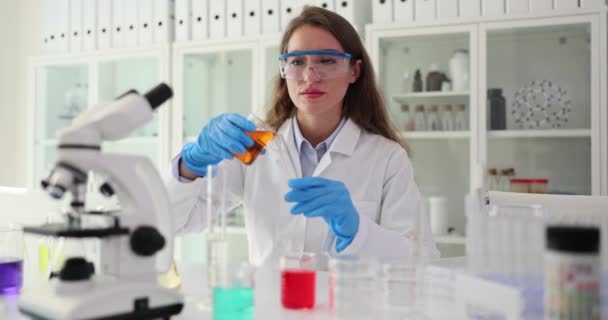 화학자는 용기에서 액체를 현미경으로 테이블에 튜브에 연구를위한 전문가 워크플로우 — 비디오