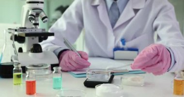 Deneyimli bir kimyager Patri kabına, laboratuardaki eylemleri belgelemek için toz madde döküyor. Mikroskop kavramına sahip uzman tablo