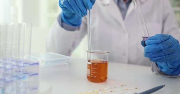 専門の実験室の労働者は実験を実施するガラス容器の試薬のサンプルを混合します 軽い診療所の遅い動きの液体を混合して下さい — ストック動画