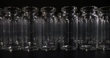 Aşılar için boş cam şişeler masa yüzeyinde karanlık bir şekilde duruyor. Tıbbi amaçlar ve laboratuvar araştırmaları için profesyonel cam eşyalar.