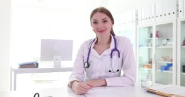 Pozitif kadın doktor klinikte ekipmanlarla başarılı bir şekilde görüştükten sonra not alıyor. İş yerinde steteskop uzmanı.