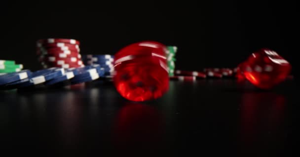 ガーマーはダーククラブの部屋に赤い透明なダイスを投げる スタジオライトの下のブラックテーブルのカジノチップとダイス プロのギャンブルゲームをプレイするための機器 — ストック動画