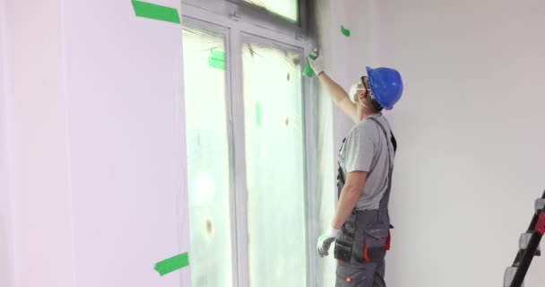 Männlicher Bauarbeiter Sprüht Graue Farbe Auf Fensterrahmen Von Wohnungen Handwerker — Stockvideo