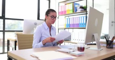 Yorgun kadın sekreter bilgilerin miktarından olumsuz duygular alan belgeleri inceliyor. Şirket ofisinde aşırı çalışma ve yorgunluk.