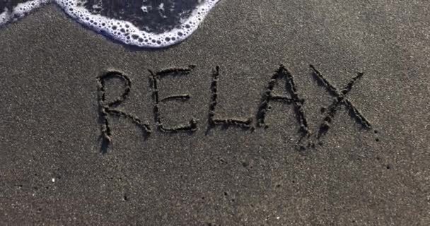 Palavra Relaxe Areia Escura Lavada Por Ondas Mar Tempo Ensolarado — Vídeo de Stock