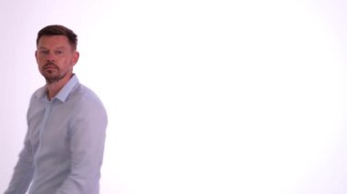 İnsan hayali aynadaki görüntüyü narsistik bir şekilde inceler. Kahverengi saçlı yetişkin erkek stüdyoda düğmeleri iliklenmemiş gömleğiyle gururla yürüyor.