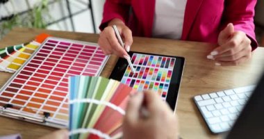 A woman in the office shows a color scheme, a close-up, slowmotion. Design studio, color choice, meeting