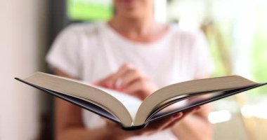 Bir kadının elinde açık bir kitap var, yavaş çekimde. Kütüphane, devamsızlık eğitimi. Bukinist, edebiyat