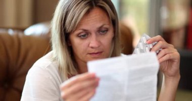 A young woman at home reads instructions for tablets, a close-up, slowmotion. Taking medications, dosage
