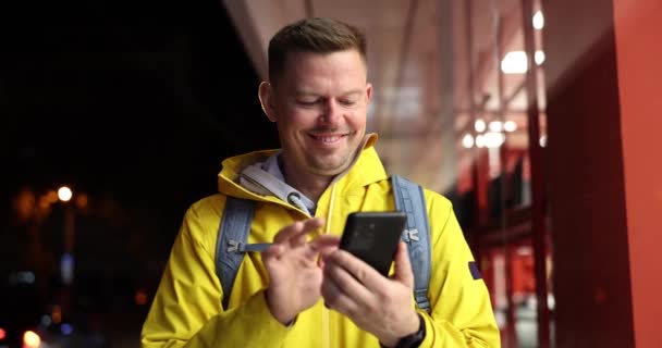 Счастливый Человек Вечером Улице Смотрит Смартфон Замедляясь Навигационное Приложение Маршрут — стоковое видео