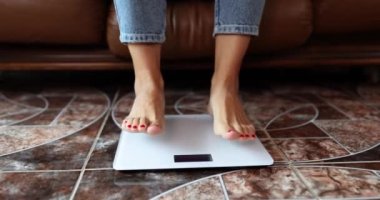 Female legs in jeans stand on electronic scales, close-up. Diet control. Weight measurement concept