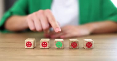 On the table in a row, wooden cubes with emotions, a close-up, slowmotion. A woman chooses positive