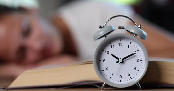 一个女人带着一本书和一个闹钟 一个特写镜头 睡在一张桌子旁 考试的准备工作 — 图库视频影像
