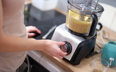 Kadın yemek işlemcisinin hızını ayarlıyor. Mutfaktaki pasta şefi mikser ya da yemek işlemcisi konseptini açıyor.