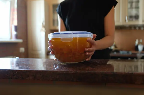 Housewife holding plastic container with soup in her hands closeup. Food storage at home concept