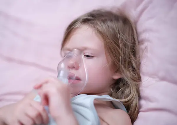 Little girl making inhalation of hormonal drug using nebulizer. Treatment for attacks of bronchial asthma and stenosing laryngitis in children concept