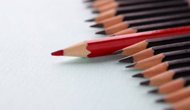 Kırmızı kalem beyaz arka planda siyah arkaplanda duruyor. İş dünyasında liderlik vasıfları