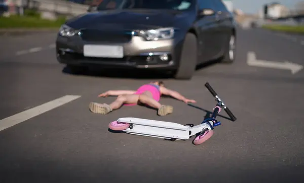 Girl lies on pavement after collision with cars on scooter. Accident with child pedestrian concept