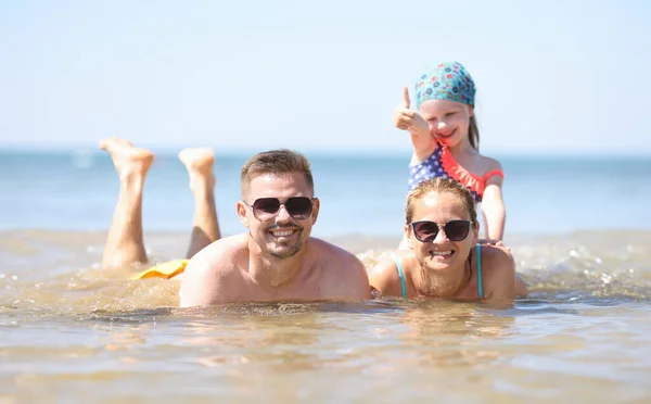 Family with little girl lying in sea. Family vacation concept