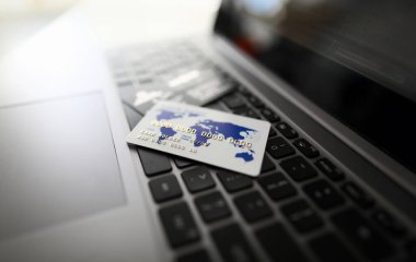 Beyaz plastik kredi kartı siyah dizüstü bilgisayar klavye arka plan üzerinde yatıyor. Online mesafeli alışveriş konsepti