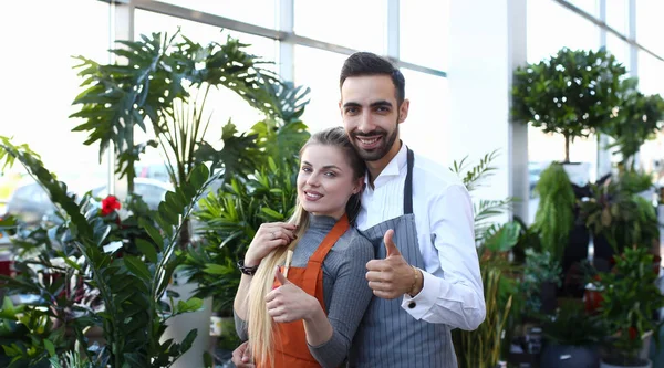 Florist Man and Woman at Domestic Flower Shop. Smiling Gardener Standing in Gardening Center with Green Home Tree and Plant. Botanic Store with Beautiful Natural Flora Looking at Camera Shot