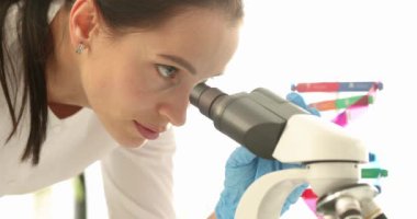 Genç bilim kadını laboratuvarda mikroskoba bakıyor. Kimyasal araştırma konsepti