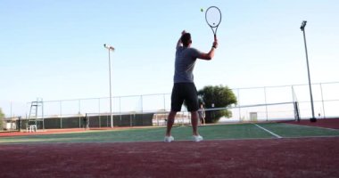 Kendine güvenen genç tenisçi raket ve top tutuyor ve sahaya vuruyor. Tenis oyunu ve tenis topu oyunda