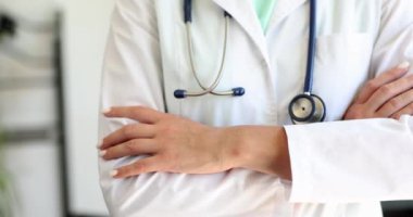 Beyaz önlüklü doktor ya da kardiyolog steteskoplu çapraz kollarla ayakta duruyor. Hastalara sağlık sigortası ve yardım