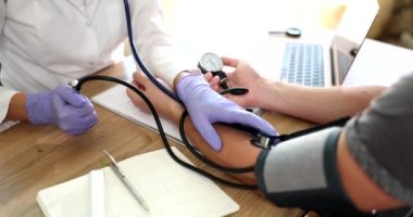 Doktor kardiyolog klinikteki adamın kan basıncını ölçüyor. Tansiyon kontrolü ve kardiyovasküler hastalık