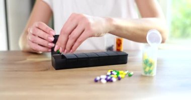 Haplar için plastik organizatör kutusuna hap koyan bir kadının elleri. İlaç konsepti vitaminler ve sağlık