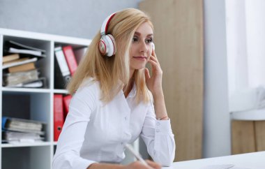Güzel kız öğrencinin öğrenme ve müzik kulaklık ile. Kalem elini ve laptop monitör arıyor tutun