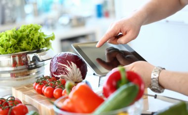 Tablet Gösteren Vegan Sebze Salatası Tarifi. Şef El Pişirme Kırmızı Organik Domates ve Lahana Ahşap Tahta üzerinde. Blogger Tablet Üzerinde Sağlıklı Gıda Kayıt. Tencerede Marul Yatay Fotoğrafçılık