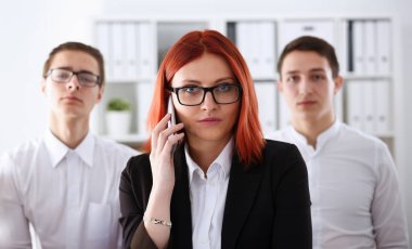 Ofis portre işkadını konuşma cep telefonu gülümseyen güzel kızıl saçlı. Kalış temas pazarlık toplantı iş beyaz yakalı yoğun yaşam tarzı elektronik cihaz mağaza mesleki eğitim konsepti