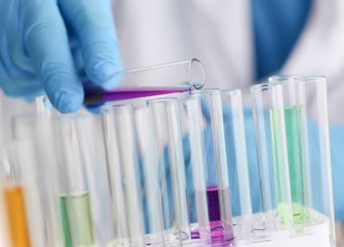 Erkek bir kimyager elinde cam test tüpü tutarak potasyum permanganatın sıvı çözeltisini taşır. Kimyasal imalatı kullanarak çeşitli reaksiyonlar uygular.