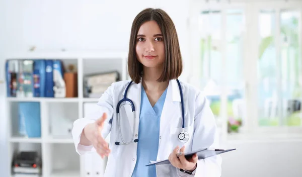 Female medicine doctor hold pad and give arm to shake in office closeup. Friend welcome introduction or thanks gesture test work examine patient congratulation help exam teamwork deal concept
