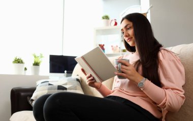 Genç çekici Hintli genç kız kanepe resme yalan çay içmek açık kitap içine bakmak. Güzel kadın kanepe üzerinde kullanmak ajandam Özet Sınav Hazırlık teslim kavramı