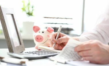 Erkek eller aile bütçesi hakkında gümüş kalemle notlar alıyor.