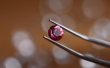 Atölyedeki kuyumcu cımbızda pembe taş tutuyor. Gemstone işleme konsepti