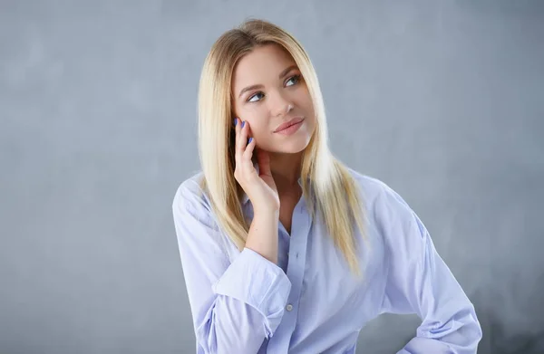 Portrait of a sexy woman in a mans shirt wearing on a gray background looks at the camera and smiling look advice to give wants objections are not accepted.