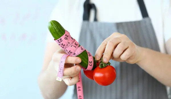 Culinary Chef Measure Green Cucumber Penis Size. Man in Apron with Tomato and Cucumber Wrapped in Centimeter. Measurement of Grocery Ingredient. Male Hand Holding Food Partial View Photography