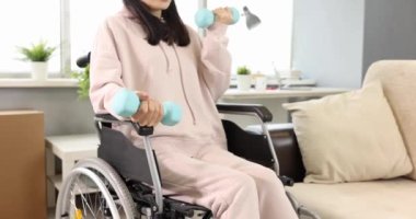 Genç bir kadın tekerlekli sandalyede otururken el egzersizi yapıyor. Engelliler için fiziksel egzersiz konsepti